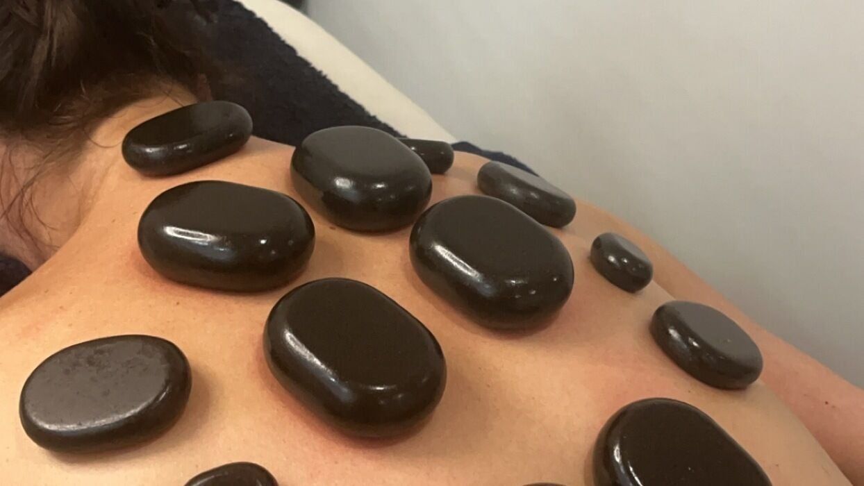 Smooth black hot stones laid along a client’s back and shoulders